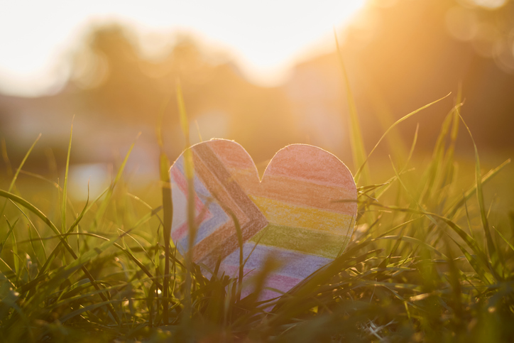 New LGBT pride flag in the shape of a heart, with sunlight on the back.